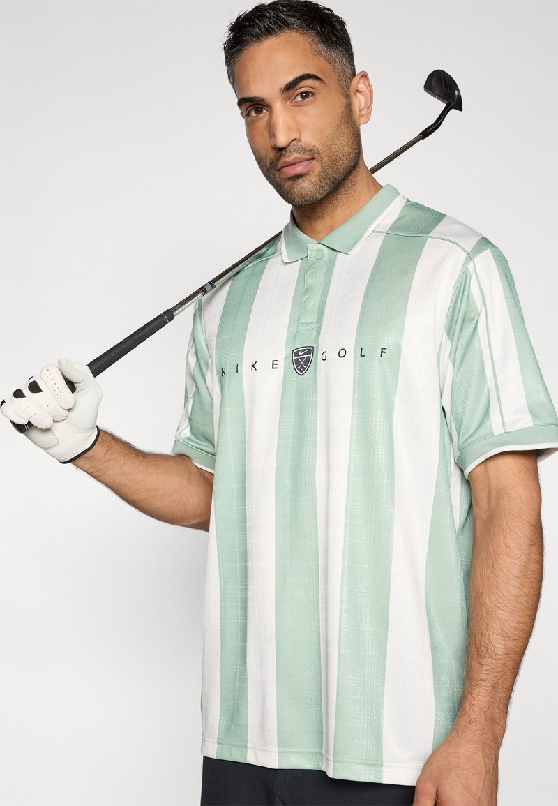 Polo de golf rayé vert clair et blanc, manches courtes, tissu texturé, avec un logo et un col à revers.