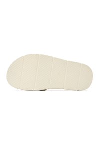 Semelle d'une sandale beige avec six larges rainures horizontales et motif texturé sur fond blanc uni.