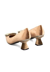 Par de zapatos de mujer de terciopelo beige de tacón bajo con tacones acampanados y hebillas decorativas de joyas en la punta.