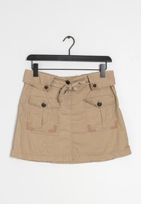 Jupe kaki avec une taille cintrée et un lien à l'avant. Elle comporte deux poches avant avec des accents marron et des boutons foncés, confectionnée dans un matériau doux.