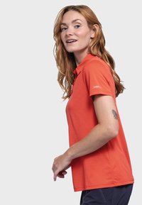 Kurzärmliges Poloshirt in leuchtendem Orange, aus leichtem Stoff mit strukturierter Oberfläche. Mit klassischem Kragen und Logo auf dem Ärmel.