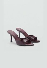 Bordeauxfarbene High-Heel-Mules aus glänzendem Leder, mit offener Zehenpartie, geschwungenem Riemendesign und schlankem Absatz.