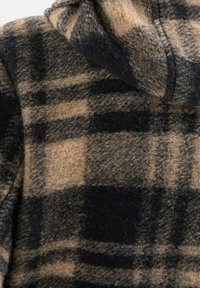 Fleece hoodie met een bruin en zwart ruitpatroon, voorzien van een zachte, gestructureerde afwerking en opvallende stiksels langs de naden.