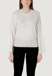 Maglione a collo V, con maniche lunghe, di colore bianco, con un motivo a rombi testurizzato, polsini e vita a costine. Abbinato a pantaloni neri.