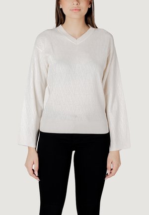 Maglione a collo V, con maniche lunghe, di colore bianco, con un motivo a rombi testurizzato, polsini e vita a costine. Abbinato a pantaloni neri.