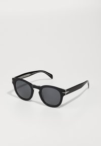 Mustad prillid ümmarguste läätsede ja paksu raami ning diskreetsete hõbedaste aktsentidega. Läikiv viimistlus ja sile tekstuur. Stylish klassikaline disain.