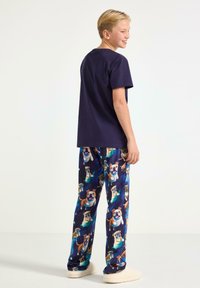 Marineblå t-shirt med korte ærmer kombineret med blå pyjamashorts med farverige hundetryk, blødt stof og en afslappet pasform.