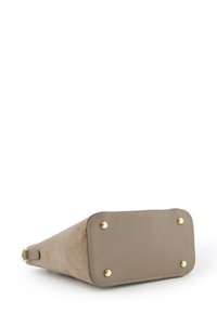 Beige suède handtas met een gestructureerde afwerking, gouden hardware accenten en vier metalen voeten voor stabiliteit. Hoekige vorm die aan één kant smaller wordt.