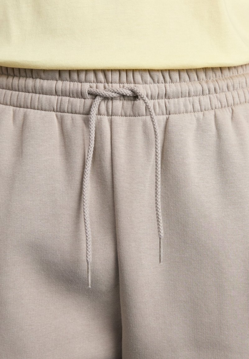 Helle beige Sweatpants mit elastischem Bund und verstellbarem Kordelzug. Der Stoff ist glatt und weich mit einer feinen Textur.