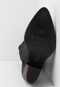 Botín de ante negro con punta afilada y suela de goma texturizada. Presenta el logo en relieve "Felmimi" y un tacón bajo en bloque.