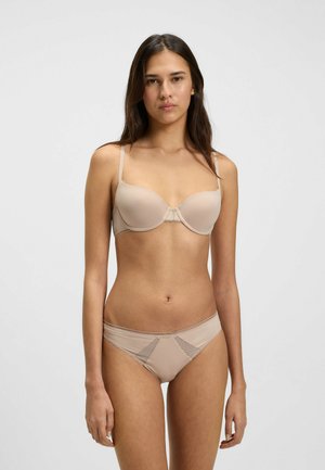 Beige bh en slipset gemaakt van zachte stof. De bh heeft gepadde cups en verstelbare bandjes; de slip heeft kanten details en een lage taille.