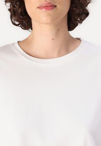 T-shirt blanc à manches courtes avec un col rond. Fabriqué en tissu doux, il présente une texture lisse et un design simple et minimaliste.