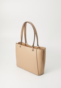 Borsa tote beige con texture liscia, manici marroni a contrasto, accessori in argento e design strutturato. Presenta una chiusura zip e un ampio interno.