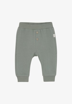 Groene katoenen broeken met geribbelde boorden, voorzien van twee houten knopen aan de voorkant en een klein wit label aan de zijkant. Zacht, casual ontwerp.