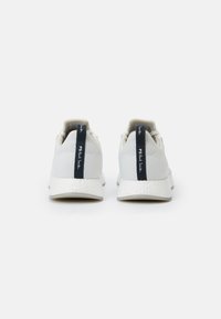 Paire de baskets blanches en maille avec languettes noires au talon portant l’inscription PS Paul Smith, vues de dos sur fond blanc.