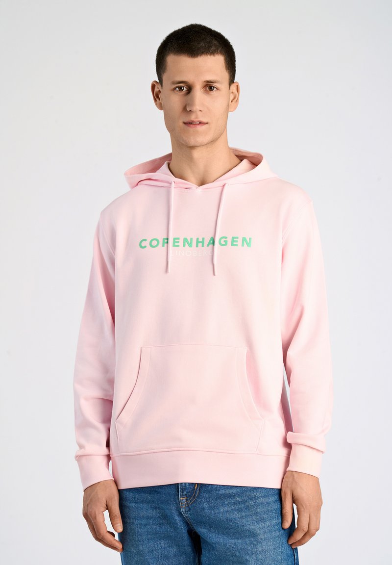 Ljusrosa hoodie med känguruficka, med grön text "KÖPENHAMN". Tillverkad av mjukt tyg, den har en huva med dragsko och ribbade ärmslut.
