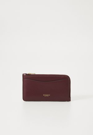 Burgundy leather wallet with a zip closure, featuring a smooth texture and gold "COACH" branding on the front. Simple, rectangular design.