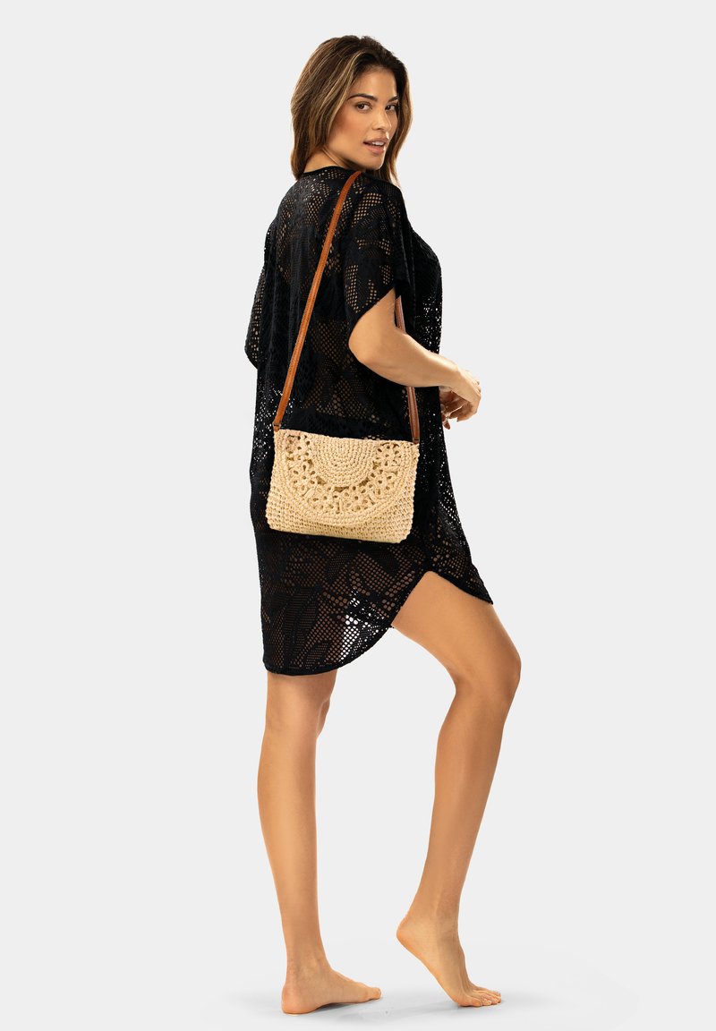 Czarny szydełkowy kaftan z szerokimi rękawami, o luźnym, przewiewnym kroju. Połączony z brązową szydełkową torbą o okrągłym wzorze.