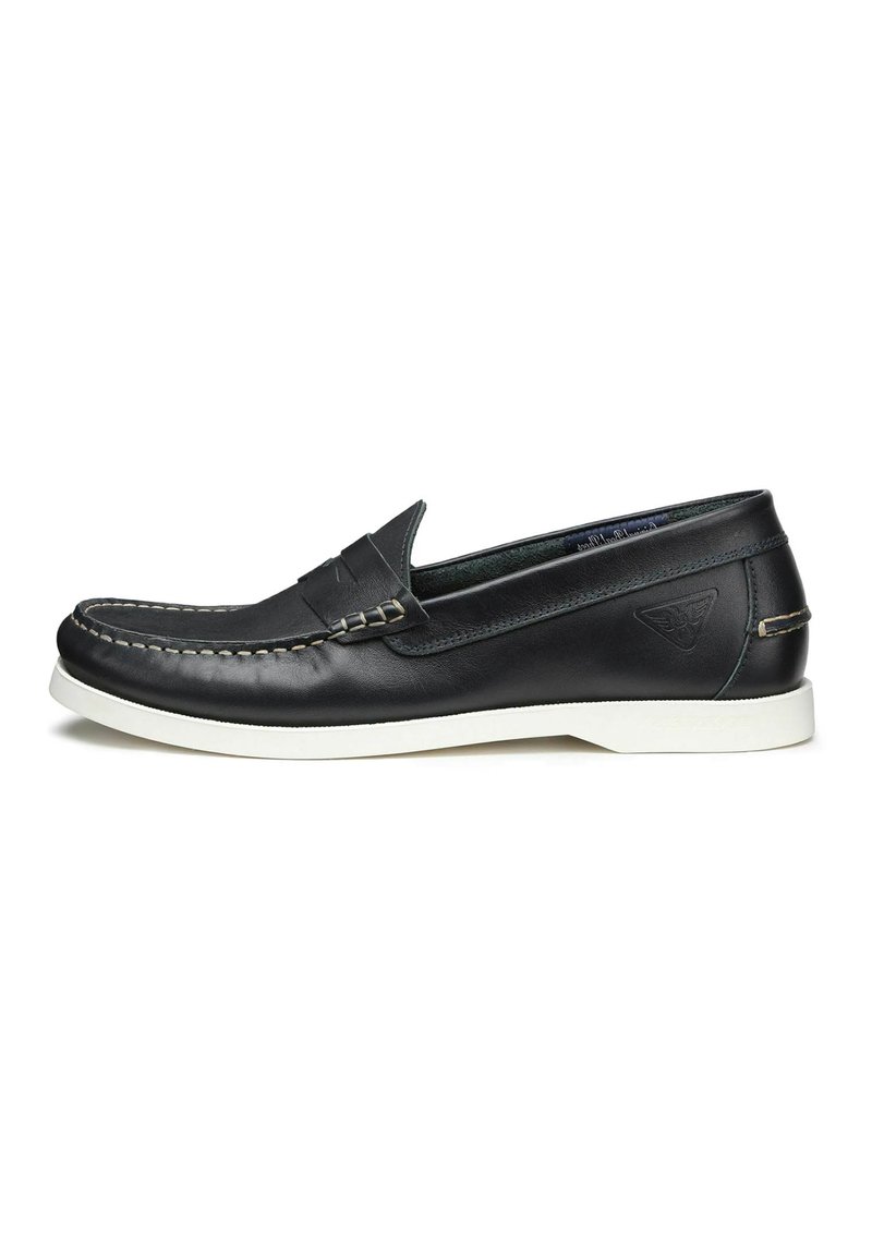 Scarpa slip-on in pelle nera con suola in gomma bianca, cuciture dettagliate e design frontale stile mocassino. Presenta un piccolo logo sul tallone.