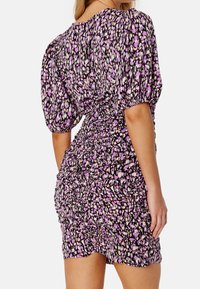 Robe courte à manches bouffantes avec un fond noir et un motif dispersé de formes abstraites roses et blanches ; la texture froncée améliore l'ajustement.