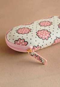 Kinnituseta prillide kott heledas beežis, millel on roosa lillemuster ja mustad täpid; sellel on roosa tõmblukk ja kuldne detail.