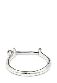Pulsera de metal plateado con una forma ovalada ligeramente irregular y un cierre de barra horizontal que conecta ambos extremos.
