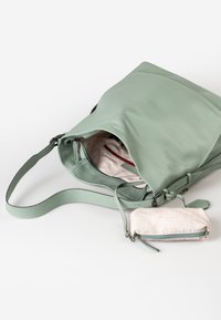 Borsa a spalla in pelle verde chiaro con zip aperta che mostra un interno beige a fantasia, con una piccola pochette beige con zip attaccata e motivo geometrico.