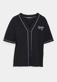 Maglietta nera a maniche corte con scollo a V, con piping bianco lungo il colletto e la patta dei bottoni, e logo "Tommy" ricamato.