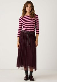 Gestreiftes Langarmoberteil in Pink und Dunkelpurpur. Plissiertes Tüllrock in tiefem Burgunder mit elastischem Bund und passendem Bindeband. Schwarze Schuhe.