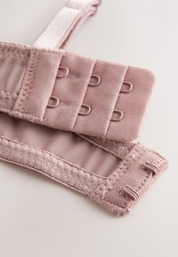 Nahaufnahme eines weichen, rosa BH-Trägers mit einem dreireihigen, zweispaltigen Haken- und Ösenverschluss und Nahtdetails.