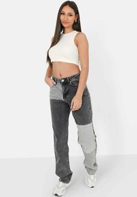 Schwarz-graue, farblich unterteilte Jeans mit entspanntem Schnitt, hoher Taille, sichtbaren Nähten und fünf Taschen.