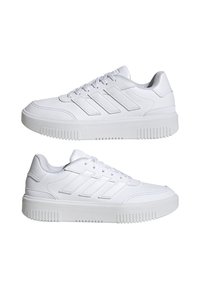 Baskets blanches en cuir synthétique avec une surface texturée, comportant trois bandes sur le côté et une épaisse semelle en caoutchouc.