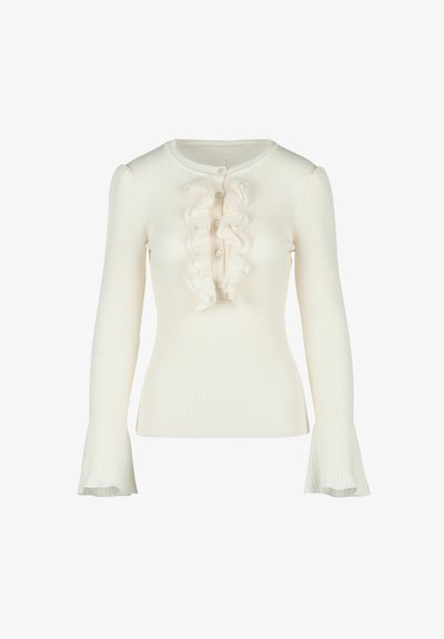 Bela reberasta dolga majica z okroglim izrezom, ki ima navpičen vrstni red gumbov in ruffled (nabrane) detajle spredaj. Rafinirani manšeti na zapestjih.