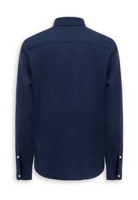Camisa azul marino de manga larga con botones y cuello clásico, mostrada desde atrás sobre un fondo blanco.