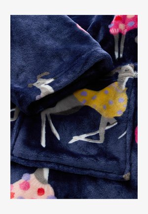 Couverture en polaire avec une base bleu marine ornée de motifs de cerfs colorés. La texture est douce, avec des robes à pois en rose et jaune.