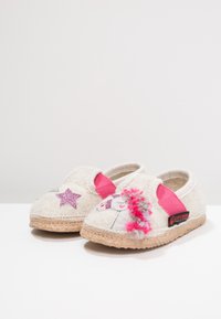 Chaussons en feutre blancs avec des bandes élastiques roses, ornés d'appliqués de licorne et d'étoiles. Semelle en liège avec des accents de pompons colorés.