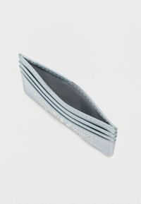 Světlé modré pouzdro na karty s několika přihrádkami, hladká kožená vnější strana, jemné šití a kontrastní tmavé vnitřní podšívání. Na přední straně je vyražený text.