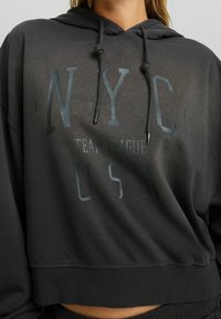 Hoodie cropped nero in morbido tessuto con grafica "NYC TEAM LEAGUE USA" in caratteri bold, con cordini e orlo a coste.