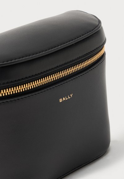 Μαύρο δερμάτινο τσαντάκι με χρυστό φερμουάρ και χρυσό λογότυπο «BALLY» στο κέντρο κάτω από το φερμουάρ, εμφανίζεται σε απλό ανοιχτό φόντο.