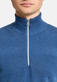 Blauer Strickpullover mit hohem Kragen und Halb-Reißverschluss. Verfügt über strukturierte Muster und Rippdetails am Kragen und an den Bündchen.