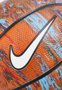 Nike košarkaška lopta s narančastom površinom, plavim i višebojnim mrljama, teksturiranim hvatom i istaknutim bijelim swoosh logom.