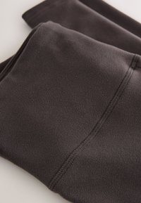 Dark gray fleece fabric folded, showing soft texture and visible stitching along the edge.