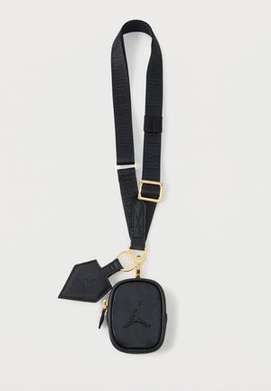 Chingă neagră reglabilă cu cataramă aurie, poșetă mică cu fermoar atașată și breloc etichetat, ambele având emboss cu logo-ul unui jucător de baschet.