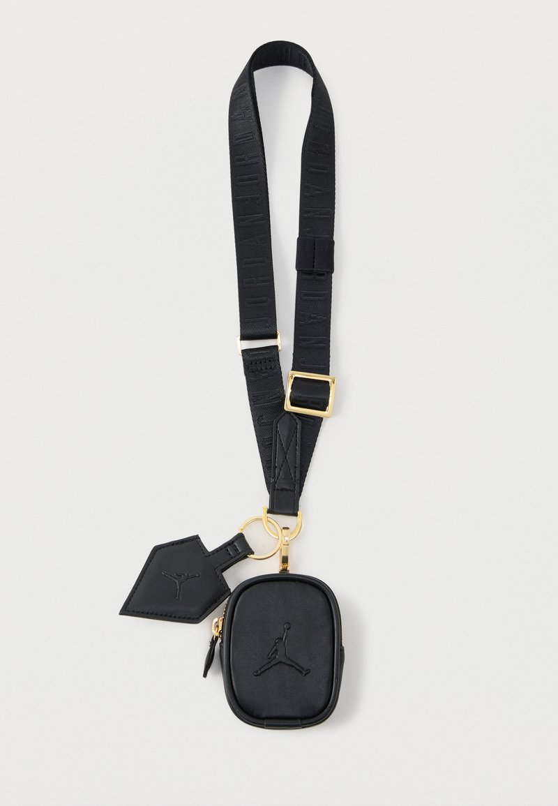 Černý nastavitelný popruh se zlatou sponou, připevněným malým zipovým pouzdrem a visačkou, obojí s reliéfním logem hráče basketbalu.