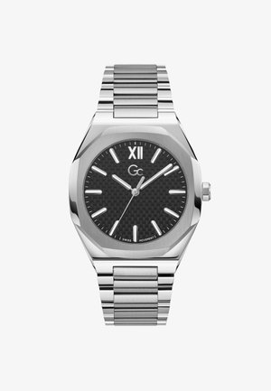 Sølvfarvet metalur med en tekstureret sort urskive, sølvfarvede timemarkører og en datovisning. Har en armbåndsrem i rustfrit stål med led.