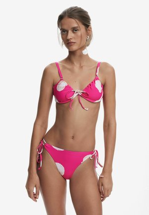 Pink bikini with white shell print; adjustable tie-front top with thin straps; matching bottom with side ties. Smooth fabric texture.