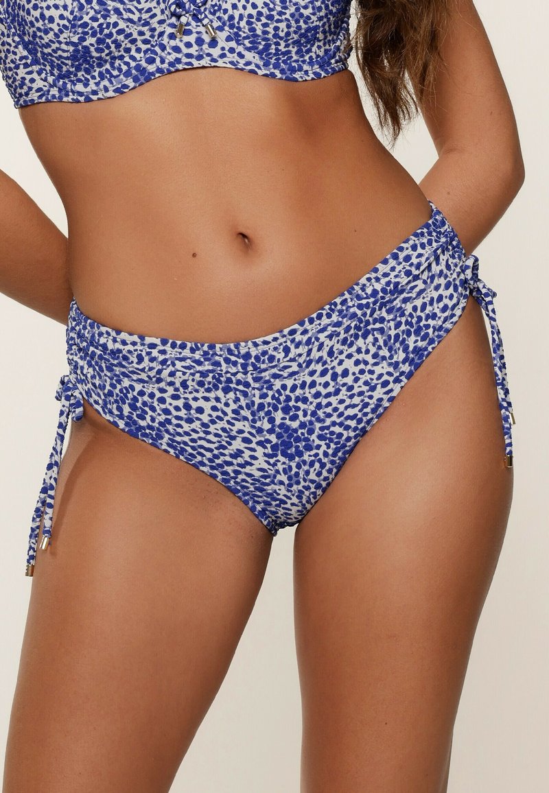 Blaue und weiße Bikiniunterteile mit einem gepunkteten Muster, seitlichen Bindebändern und einem gerafften Design, aus dehnbarem Material.