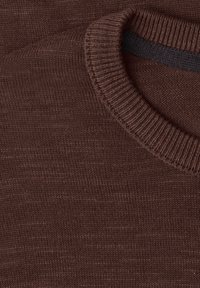 Gros plan du col rond côtelé d'un pull marron en maille et du tissu doux et texturé.