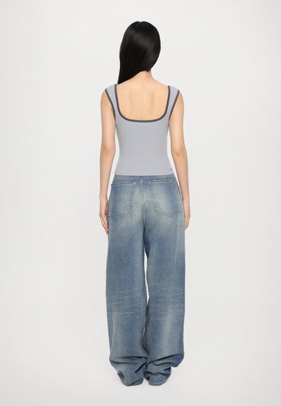 Lys grå tætsiddende tanktop med firkantet udskæring, parret med oversized blå denimjeans med en falmet vask og afslappet pasform.
