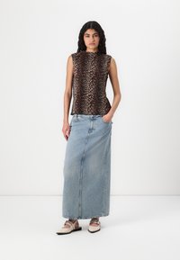 Top senza maniche con stampa leopardata, abbinato a una lunga gonna in denim azzurro e scarpe beige con cinturini; tessuto morbido e vestibilità rilassata.